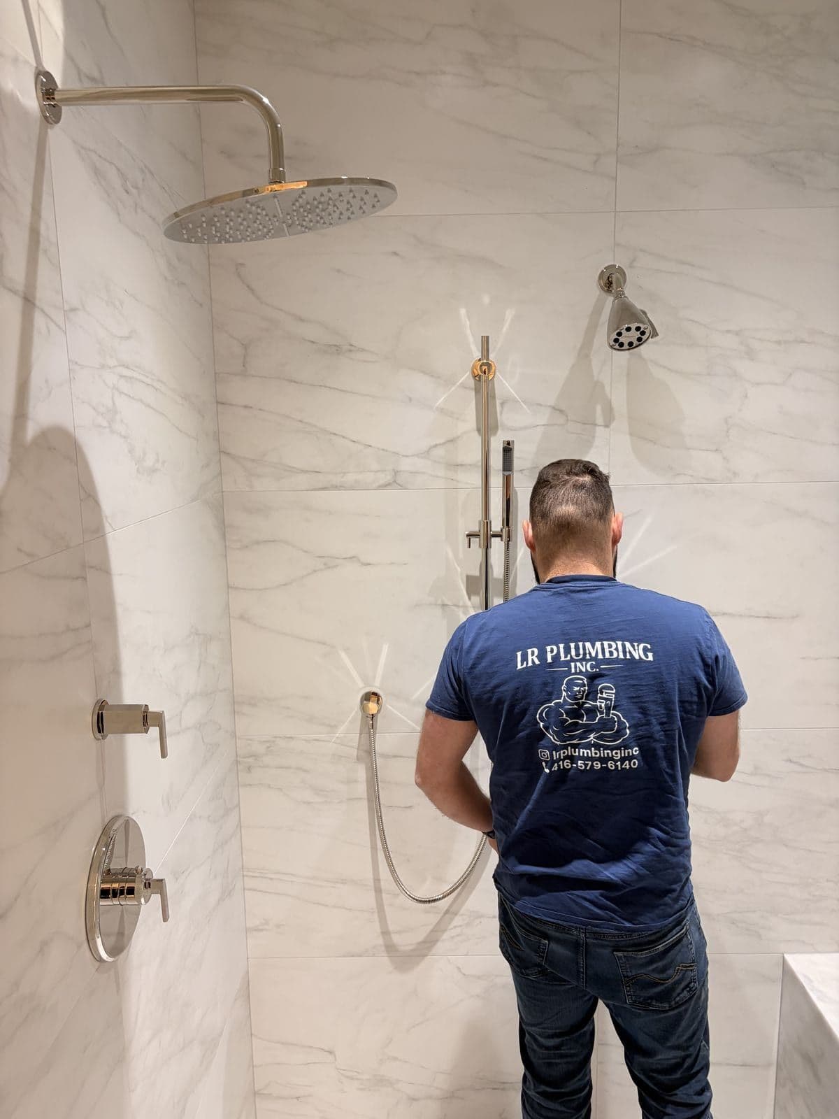 LR Plumbing installing a rain shower head and hand shower in a marble bathroom in Toronto
